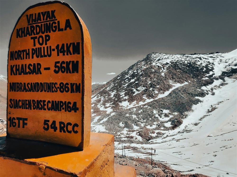 Khardung La pass signpost against snow-covered mountains